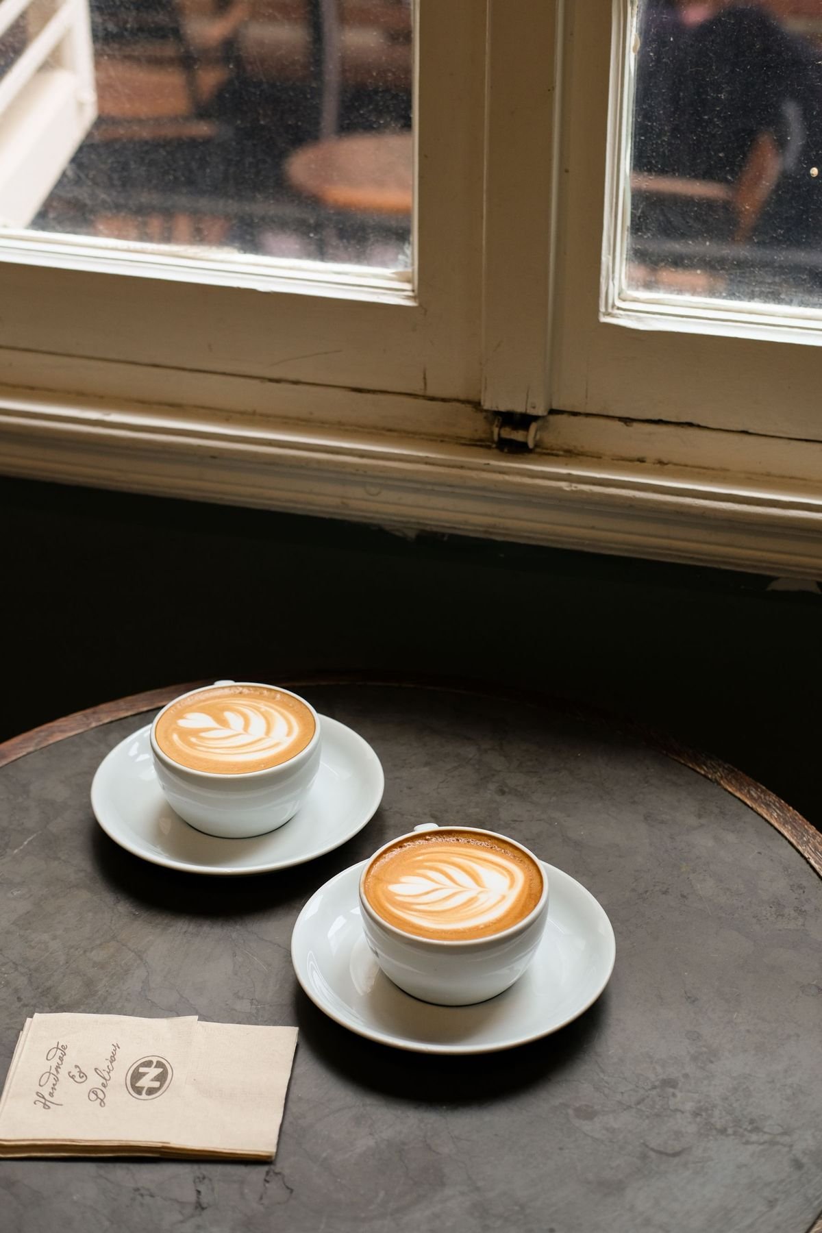 Deux cafés posés sur une table ronde près d’une fenêtre